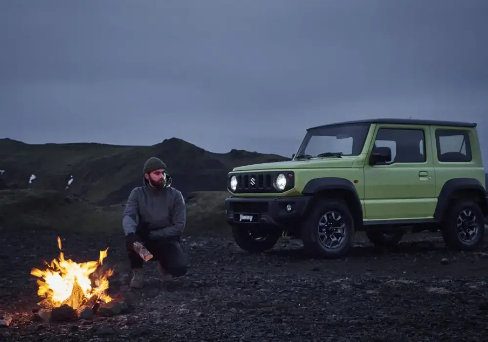 Suzuki Jimny verde claro de 3 puertas estacionado en un paisaje rocoso