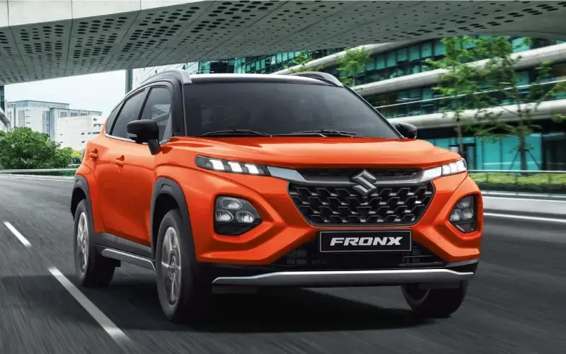 Suzuki Fronx Hybrid de color naranja conduciendo sobre una carretera asfaltada.